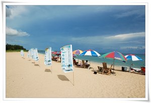 海濱線上橫排著陽傘與躺椅，水上活動玩累了可以稍做休息